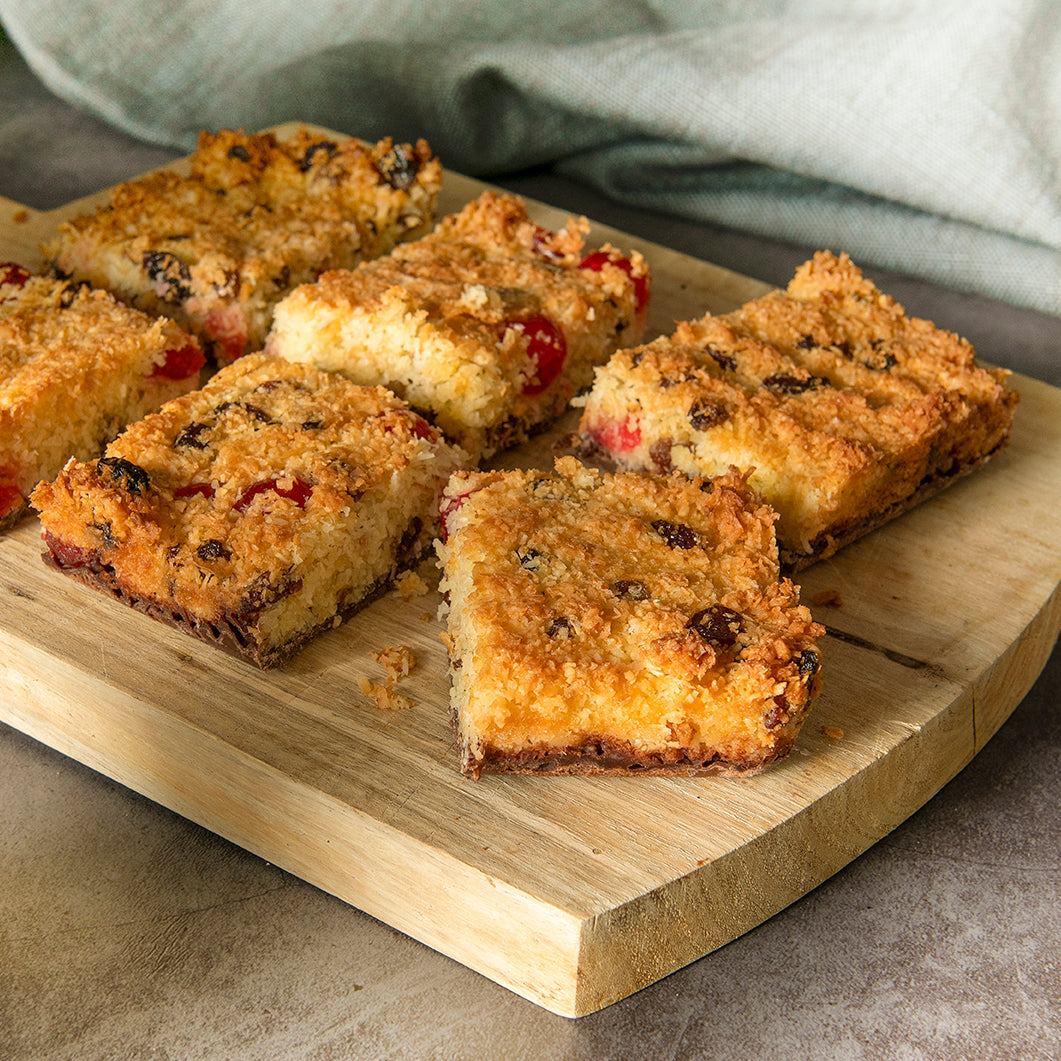 Bryson's Picnic Slices on a wooden chopping board. Made with coconut, cherries and sultanas.