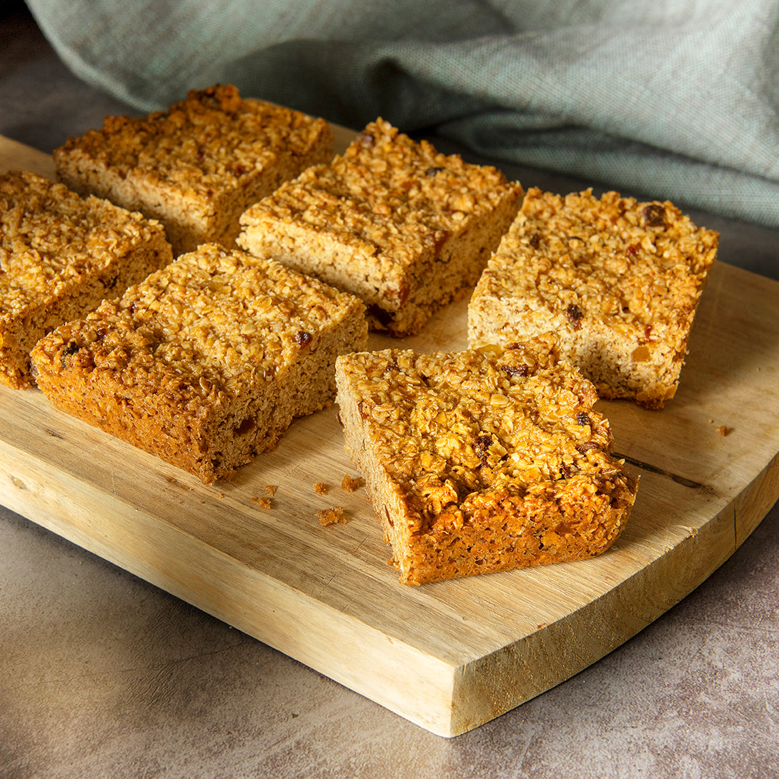 6 slices of Bryson's Fruity Flapjack on a chopping board. Made with oats, apricot and stem ginger.